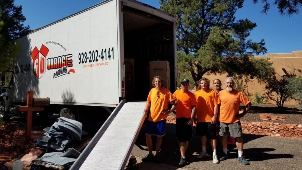 A group of men standing in front of a moving truck.