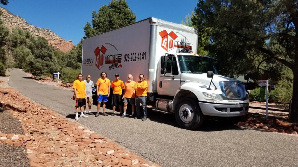 A group of people standing in front of a moving truck.
