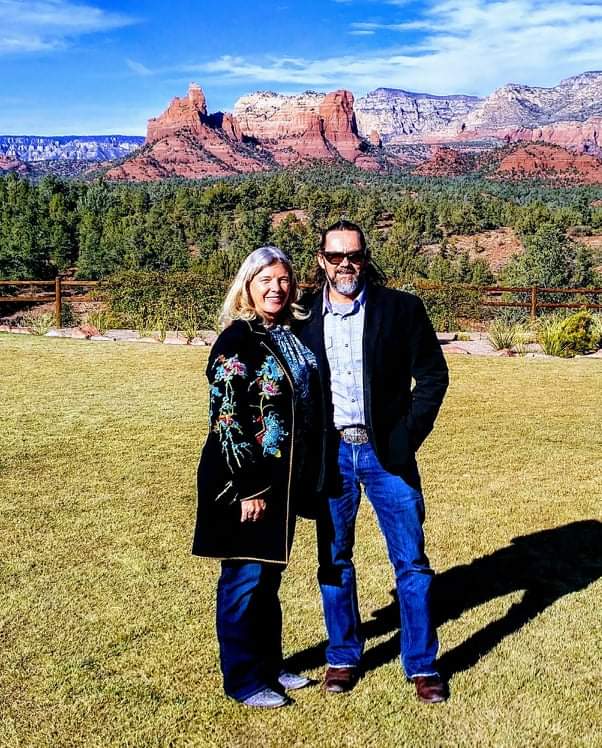 A man and woman standing in front of some mountains.